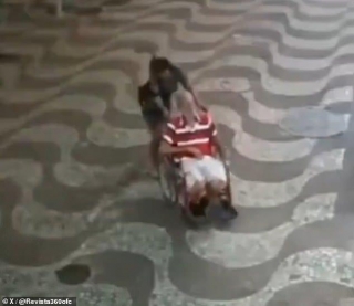 Eerie New Footage Shows Woman Struggling To Push Wheelchair-bound Man Through Streets Just One Day Before She Wheeled His Dead Body Into Bank To Sign Off A Loan