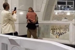 A Security Officer At Makkah Carries A Pilgrim To Show Him Holy Kaaba